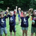 four campers holding hands in the air